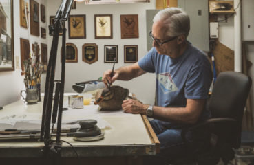 An artist paints a hand-carved duck decoy