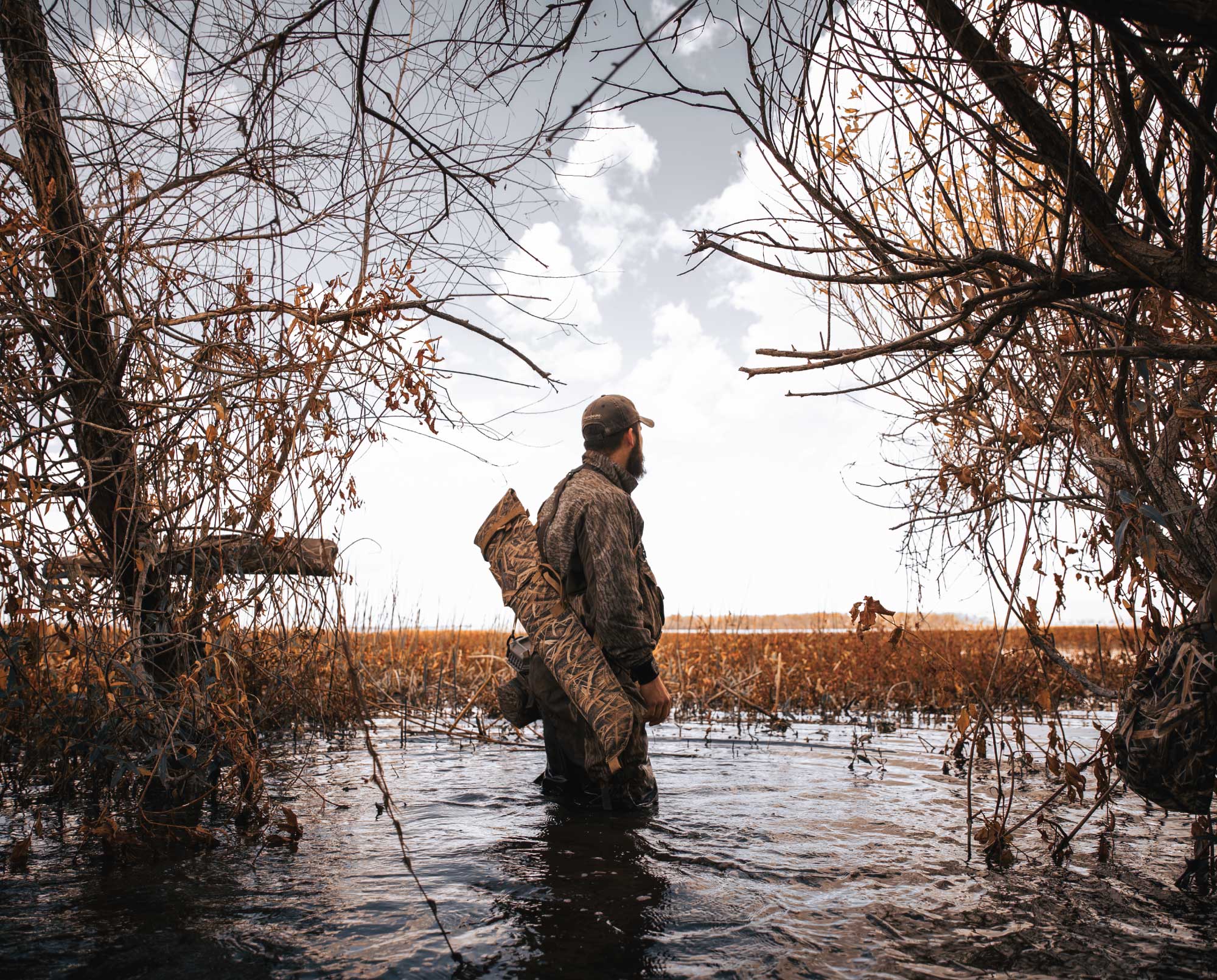 A duck hunter stands in a marsh