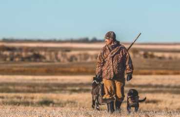 A goose hunter walks with his black lab