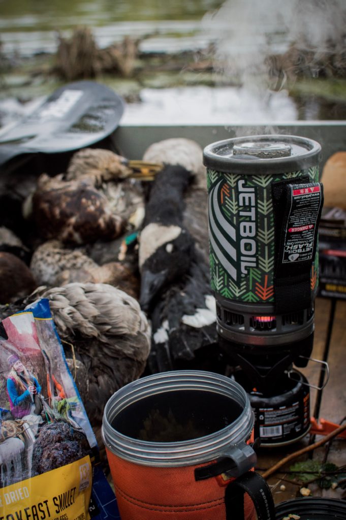 A duck hunter using camp gear at the duck blind. 