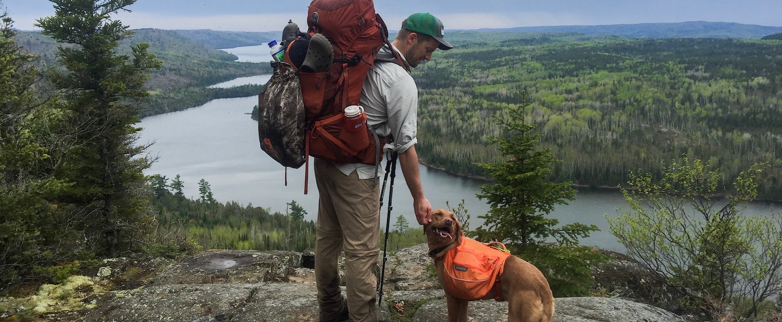 A hiker wearing a backpack and his dog