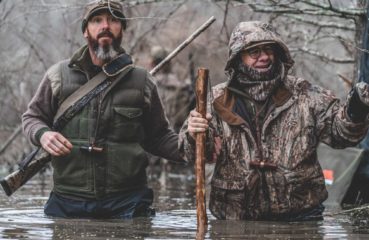 Two duck hunters wade through flooded timber