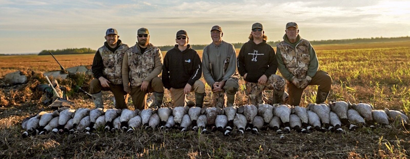 Goose hunters pose with a stack of Canada geese