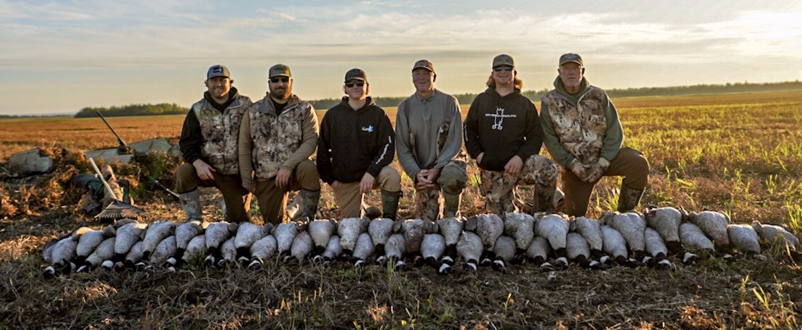 Goose hunters pose with a stack of Canada geese