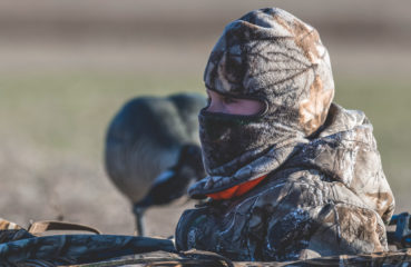 A young duck hunter dressed in camo waits in a layout blind